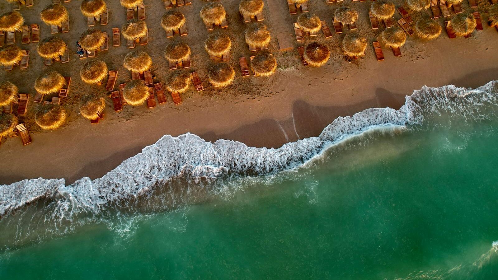Vue aérienne d'une plage avec parasols en paille et eau turquoise